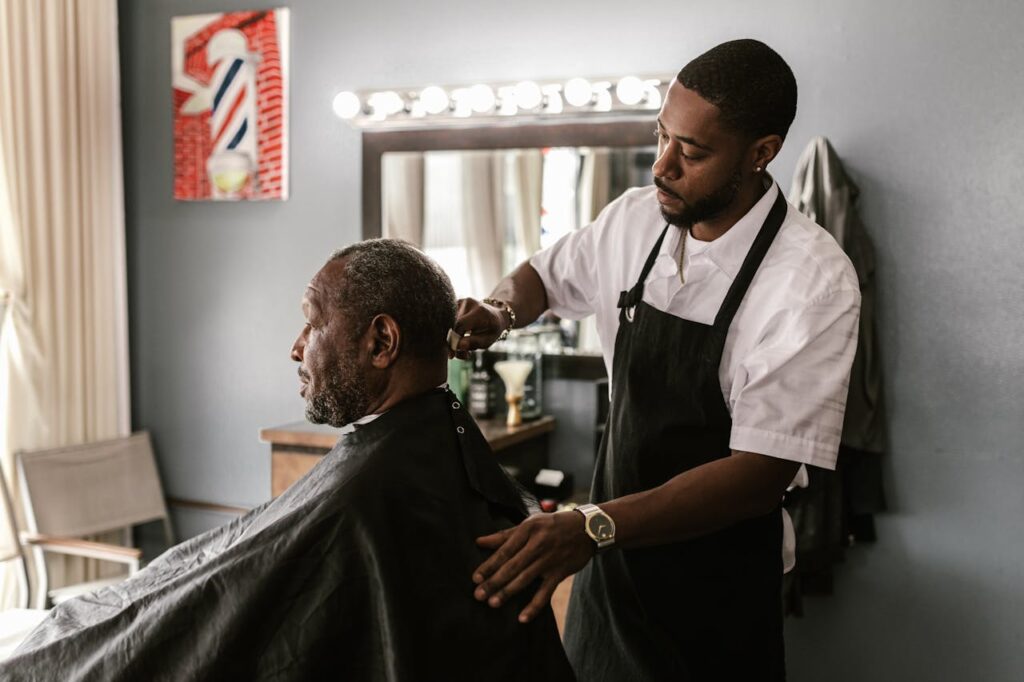 A barber meticulously trims a customer's hair in a stylish barbershop setting.